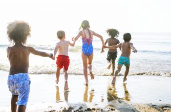 niños jugando en la playa con juguetes de arena y cubos actividades de verano para niños