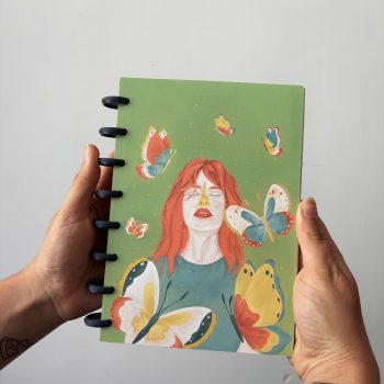 Portada de la libreta ilustrada Habitar de Nazaret Moreno con mujer pelirroja y mariposas sobre fondo verde
