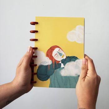 Libreta ilustrada Respira de Nazaret Moreno con portada amarilla, mujer pelirroja y nubes