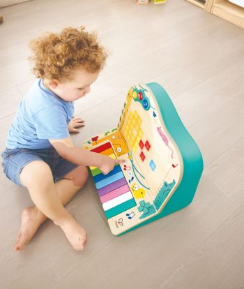 Niño jugando con el piano interactivo Dynamic Pixel Piano Arcade de Hape y sus teclas de colores.
